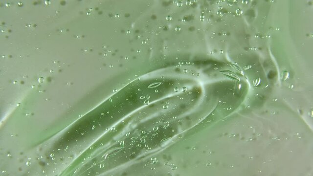 Green liquid cream, cosmetic gel fluid, smear motion on a surface. Beauty skincare product sample. Top view. Slow motion. High quality 4k footage