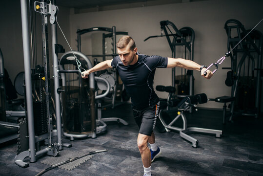 Young man doing chest exercise with cross machine.