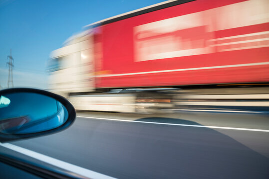 Blurred motion of truck moving on road seen through car window