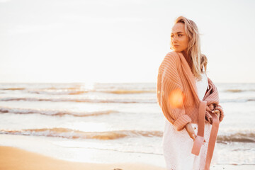 Young slim woman walk alone on the beach or ocean and look at the horizont. Female dressed in a...