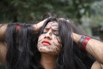 A southeast Asian brown woman protesting gender based violence by writing anti violence against...