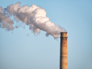 Dense smoke and steam coming out from the industrial chimney. Environmental Pollution concept.