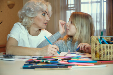 Mature mother and her daughter drawing together, doing homework at home, selective focus