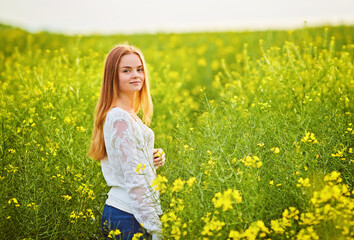 Naklejka na ściany i meble Redhead girl in a rapeseed field