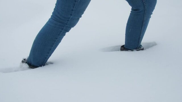 Legs walking on snow with footprints. side view. camera follows the legs