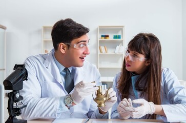 Two archeologists looking at ancient gold lamp