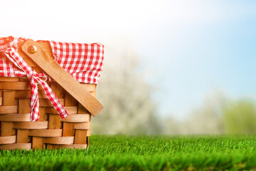 Picnic basket on the grass on the background of nature. Relaxation and summer mood. Departure for a...