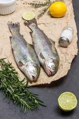 Raw trout fish with rosemary sprigs and lemon wedges