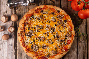 Italian pizza top view on wooden background. Cheese, olives and tomatoes ingredients. Background for culinary recipes.