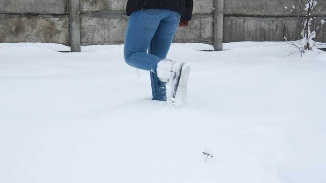 Legs walking on snow with footprints. Woman paves the way through a snowy field