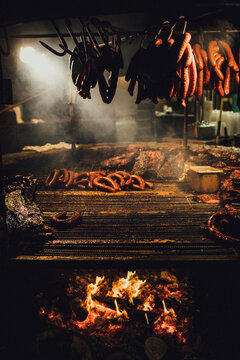 Sausages being cooked on metal grate over fire