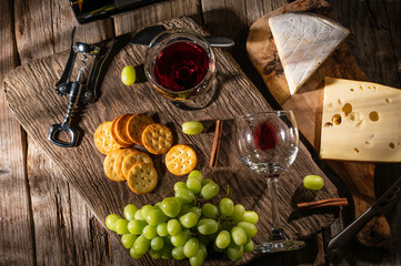 Fototapeta na wymiar Cheese tasting, different types of cheese with red wine, grapes and snacks. Wine food and romantic, cheese delicacies. Menu design horizontally. View from above.