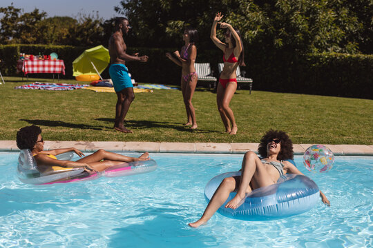 Diverse group of friends having fun and dancing at a pool party - Powered by Adobe