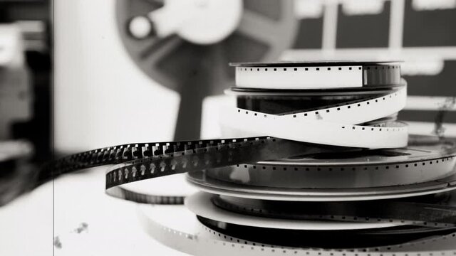 Movie film cinema background, editing table with heap of 8mm reels black and white old vintage scratch and dust film effect