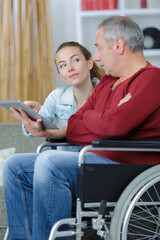 young lady showing tablet screen to disabled man