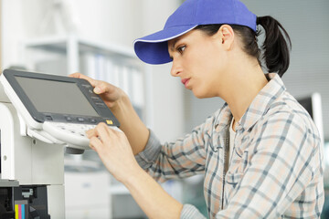 happy woman smiling at the camera fixing a printer