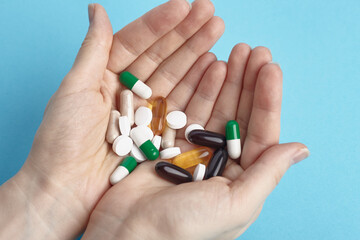 Closeup of white pils and colorful capsules on a hands.