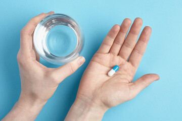 Top view of capsule on a hand on a blue background. Heap of pills - medical background