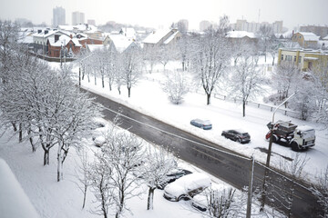 Snowy winter city view from the window. Snowstorm and snow covered street and cars.