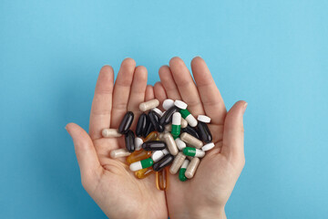 Closeup of white pils and colorful capsules on a hands.