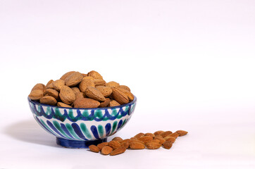 almonds in a ceramic bowl on a white background. Horizontal