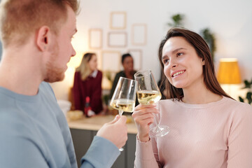 Happy young brunette woman clinking flute of champagne with that of boyfriend