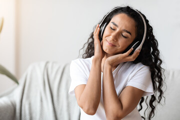 Emotional young woman in wireless headphones enjoying music