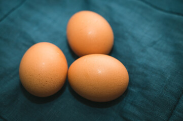 Top view of fresh brown raw chicken eggs on blue fabric. Ingridients for food. Preparation for Easter.