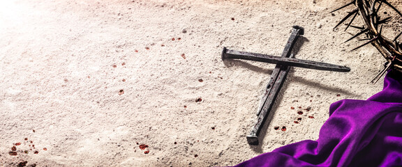 Three Nails In Shape Of Cross With Purple Robe, Crown Of Thorns And Blood Drops On Dirt Floor -...