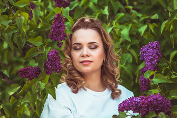 The woman around a blossoming purple lilac in the garden