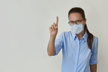 On the right side of the image is a woman wearing a medical face mask and a blue shirt, pointing her finger at an empty space