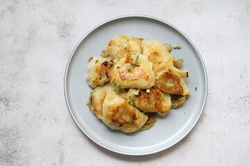 fried dumplings, crispy dumplings with fried onion, round plate full of hot dumplings sprinkled with green onions