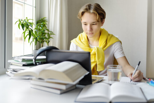 Teenager Boy Study At Home. Online Education And Distance Learning For Children. School Boy Doing His Physics Homework Using Gadgets. Lessons On The Internet For High School Students