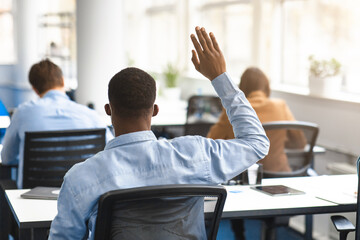 Back view of black guy student raising hand