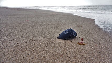 Fototapeta na wymiar Mascarilla sobre arena de playa contaminando el ambiente