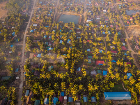 Aerial view of a small residential district with barracks and palm trees covered with fog in Mrauk-U Township, Myanmar.