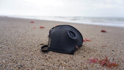 Mascarilla sobre arena de playa contaminando el ambiente