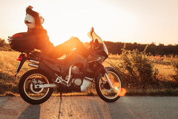 Female biker sitting on her bike, relaxing. Afternoon light, copy space