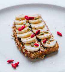 Healthy breakfast toast with chocolate peanut butter, banana, pumpkin, sunflower and flax seeds, sesame, goji berries. Copy space