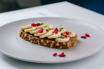Healthy breakfast toast with chocolate peanut butter, banana, pumpkin, sunflower and flax seeds, sesame, goji berries. Copy space