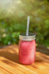 Smoothies in a glass jar with a straw. Orange, red berries and banana smoothie.