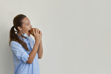 Hungry pretty woman pulled down her protective face mask to take a bite out of a vegan burger stock photo