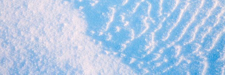 Beautiful winter background with snowy ground. Natural snow texture. Wind sculpted patterns on snow surface. Wide panoramic texture for background and design.