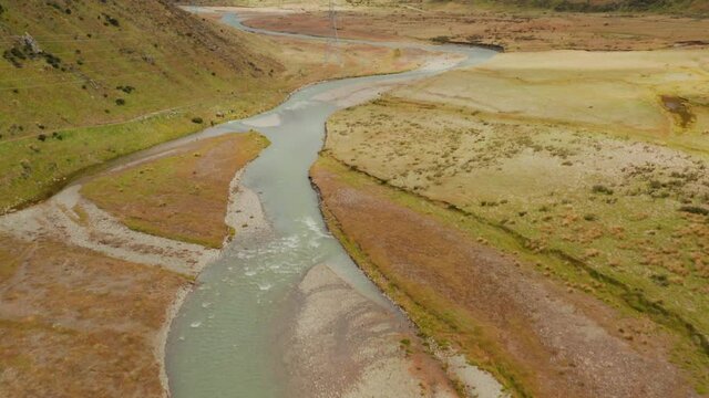 Drone tilt up shot of high voltage towers in an empty beautiful valley of New Zealand.