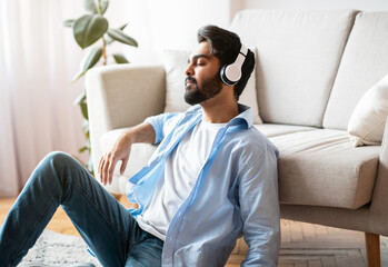 Fototapeta premium Time To Relax. Calm arab man in headphones listening music at home