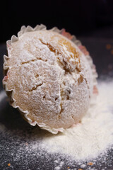 cupcake in powdered sugar on a plate on a black background