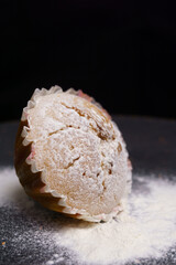 cupcake in powdered sugar on a plate on a black background