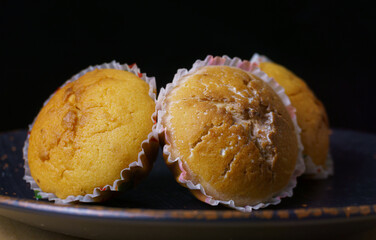 Three cupcakes on a plate on a black background