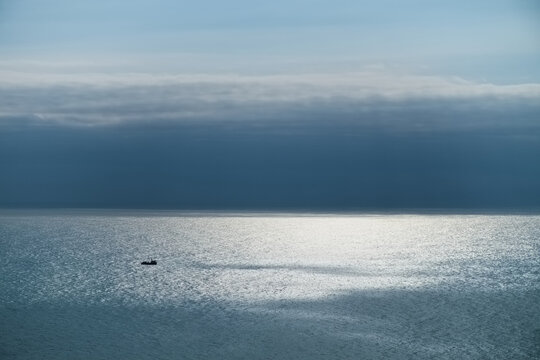 small lone ship in blue ocean sun and clouds