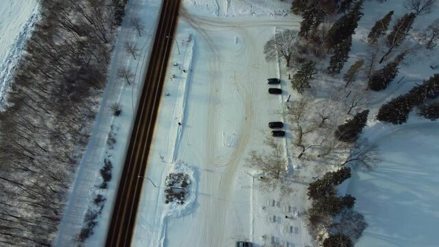 aerial winter parallel flyiover snow covered birds eye view sunset fly over North Saskatchewan River empty parking lot next largest manmade ice skating rink in Canada at Victoria Park Pavillion ice1-3